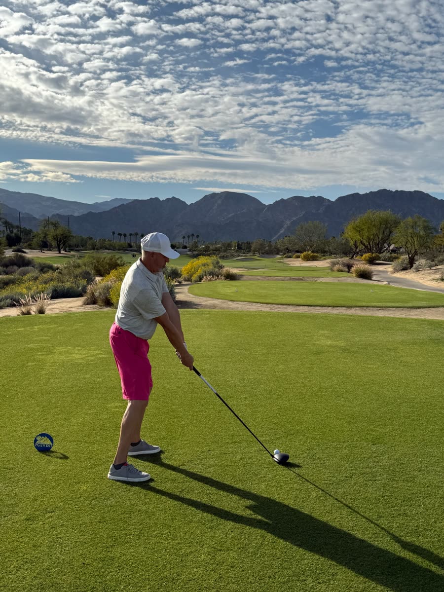 Alan lining up a drive on a desert golf course, mountains behind